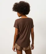 Remera deportiva de mujer Get Over, confeccionada en microfibra blanca con cuello redondo, manga corta y un diseño estampado de ondas en color verde y marrón en el lateral izquierdo.