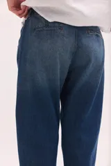 Pantalón de jean de tiro bajo y calce relajado, con cierre frontal de múltiples botones visibles y largo al tobillo.