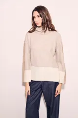 Sweater de punto con cuello alto, corte holgado y diseño color block en tonos beige y blanco.