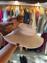 Sombrero de algodón tejido estilo fedora, color mostaza, con cinta de cuero marrón decorativa alrededor de la copa.
