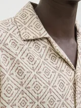 Camisa de manga corta Jack & Jones con cuello resort y cierre de botones. Diseño con estampado geométrico en tonos beige y marrón.