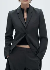 Blazer entallado de diseño largo, con cuello de solapa con muesca, cierre frontal de botones y bolsillos de solapa. Cuenta con un bolsillo de ribete en el pecho y mangas largas con puños abotonados.