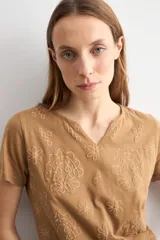 Remera marrón camel de manga corta, con cuello en V y diseño de estampado floral con relieve.
