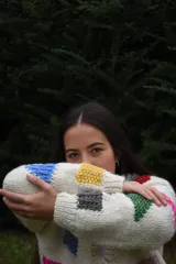 Cardigan de lana merino tejida a mano con dos agujas, color blanco con diseño de figuras geométricas en tonos multicolor y cierre frontal con botones de madera.