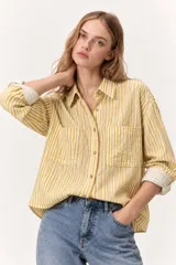 Camisa de manga larga con diseño de rayas verticales en tonos rosado y blanco, corte holgado y bolsillos frontales con solapa en el pecho.