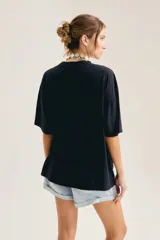 Remera oversize de algodón color blanco, con cuello redondo, mangas cortas y estampa gráfica frontal en blanco y negro con diseño vintage.