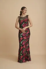Vestido largo negro íntegramente bordado con lentejuelas en tonos fucsia y verde, con diseño floral, escote redondo y transparencias en la parte superior.