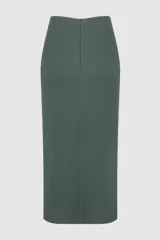 Falda midi tejida color verde oscuro, de silueta ajustada con tajo frontal en el dobladillo. Presenta un diseño drapeado en la cintura con una aplicación de pedrería decorativa y cierre posterior oculto.
