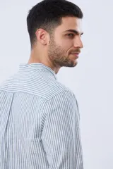Camisa de lino a rayas verticales blancas y azules, de manga larga, con cuello mao y cierre frontal de botones.