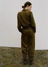 Camisa de lino color verde militar, de corte recto con cuello camisero, manga larga con puños abotonados, bolsillo de parche en el pecho y cierre frontal de botones.