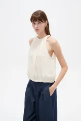 Musculosa sin mangas color natural, confeccionada en viscosa, con cuello redondo base con frunces y elástico en la parte inferior.