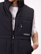 Chaleco reversible de nylon con diseño acolchado, cuello alto y cierre frontal. Cuenta con un bolsillo con cierre en el pecho y bolsillos laterales, además de una etiqueta con el logo de la marca.