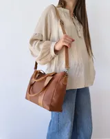 Bolso tipo tote de cuero color marrón con doble asa corta y correa larga extraíble.