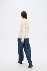 Sweater de lyocell al cuerpo, con cuello redondo a la base y mangas largas con detalle de botones en los puños.
