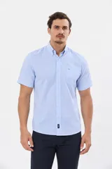 Camisa de manga corta con estampado de cuadros pequeños en tonos celestes y blancos, cuello con botones y bolsillo ojal en el pecho.