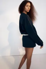 Falda pantalón de tiro bajo color azul marino, con detalle de falsos botones metálicos en el frente y cierre lateral con cremallera oculta.
