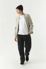 Campera bomber negra de simil gamuza, con cuello redondo, cierre frontal con cremallera, bolsillos laterales con cierre y puños elásticos.