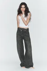 Jeans de tiro alto con diseño de pierna ancha y corte extra largo. Presenta una cintura cruzada asimétrica con cierre de cremallera y botones metálicos, además de un diseño clásico de cinco bolsillos.