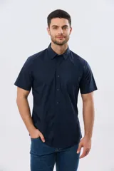Camisa lisa de algodón azul marino, de manga corta, con cuello camisero, cierre frontal de botones y un bolsillo aplicado en el pecho.