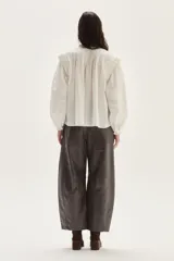 Blusa blanca de algodón con escote alto, detalles de smock y tablitas en el canesú y hombros, y mangas largas abullonadas con puños fruncidos.