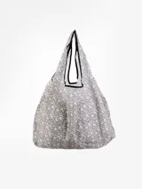 Bolsa de mandados de tela estampada con diseño floral en tonos celeste y blanco, con ribete negro en las asas.