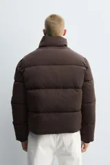 Cazadora acolchada de corte boxy fit, confeccionada en tejido técnico repelente al agua. Presenta cuello subido, cierre frontal con cremallera, mangas largas con puños elásticos interiores y bolsillos laterales de vivo.