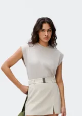 Camiseta sin mangas de tejido de punto fino, color gris claro, con cuello redondo y hombreras sutiles que aportan estructura.