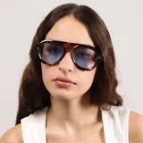 Lentes de sol con armazón de acetato negro y diseño de puente plano, estilo aviador moderno con cristales oscuros.