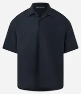 Camisa de manga corta color negro, con diseño boxy, cuello clásico y abotonado frontal.