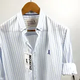 Camisa de manga larga a rayas verticales celestes y blancas, con cuello abotonado y logo bordado en el pecho. Marca Duxon.