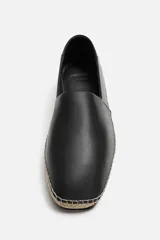 Alpargatas negras de piel con talón plegable, forro interior de piel, horma cuadrada y suela recubierta de yute.