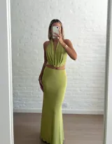 Conjunto de dos piezas color verde oliva, compuesto por un top con escote profundo y diseño cruzado, y una falda midi ajustada de tiro alto.