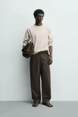 Camiseta de manga larga con cuello redondo, confeccionada en algodón compacto y pesado, con diseño de corte relajado y costuras decorativas en el cuello.