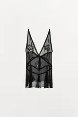 Top semitransparente negro de gasa con escote en pico, tirantes finos y detalles de bordados florales a tono. Presenta godets y acabados en puntilla, con cierre de botones forrados en la espalda.