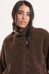 Chaqueta tipo gamulán de textura de corderito en color marrón, con cierre frontal, solapas amplias y detalles de correas ajustables en la cintura y mangas.