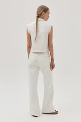 Chaleco de denim blanco con costuras en contraste color ocre, cuello camisero, cierre frontal con botones, bolsillos de parche con solapa en el pecho y sisas desflecadas.