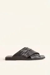 Sandalia tipo slide de cuero vacuno color negro, con diseño de tiras cruzadas acolchadas y punta cuadrada.