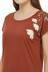 Remera de algodón negra, de corte holgado, con cuello redondo a la base y detalle de estampado floral en el hombro izquierdo.