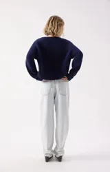 Sweater de punto fino color azul marino, con cuello redondo amplio y mangas largas con puños rectos. Presenta un corte holgado y diseño minimalista.