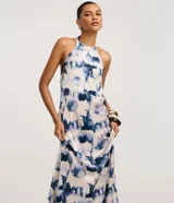 Vestido largo estilo slip con cuello halter que se ata en la nuca, sin mangas, con estampado abstracto en tonos azul y blanco que simula un efecto tie-dye.