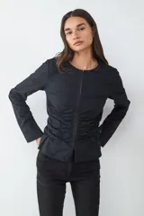 Blusa blanca de manga larga con escote redondo, cierre frontal oculto y detalles de frunces laterales en el cuerpo.