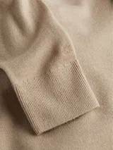 Sweater color beige de tejido de punto, con cuello alto y mangas largas.