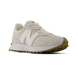 Championes New Balance 327, de color beige con el característico logo "N" en blanco en los laterales. Presentan una suela de goma con tapones que se extiende hacia el talón y detalles en gamuza y nylon.