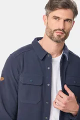 Camisa azul marino de poliéster con textura polar, corte recto, cuello camisero, cierre frontal con botones a presión, dos bolsillos de parche con solapa abotonada en el pecho y puños abotonados.