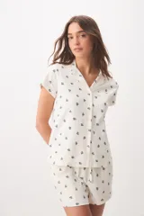 Pijama de algodón color blanco con pequeño estampado floral azul, compuesto por una camisa de mangas cortas con cuello solapa, botones frontales y bolsillo en el pecho, y un short con elástico y lazo ajustable en la cintura.
