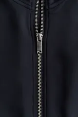 Campera deportiva corta de punto grueso con leve brillo, cuello elevado, cierre frontal y bolsillos laterales insertados.