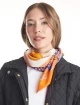 Pashmina cuadrada de satén con estampado multicolor en tonos naranja, azul y crema. Presenta un diseño geométrico y figurativo, con bordes definidos.