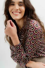 Camisa de crepe con estampado geométrico de hexágonos en tonos bordó, marrón y blanco. Presenta cuello camisero clásico, cierre frontal con botones y mangas largas con puños abotonados.