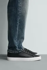Zapatilla de estilo minimalista con cordones, confeccionada en material sintético de acabado mate. Presenta una horma redonda, forro interior en tono contrastante y suela de goma con textura ligera.