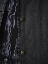 Trench largo de denim gris lavado, de silueta recta y amplia, con solapas amplias, mangas largas y botonadura frontal.